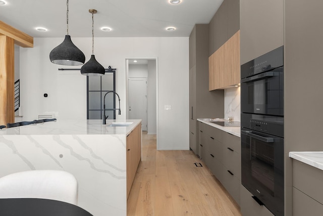 kitchen featuring a sink, decorative backsplash, light wood-style flooring, black appliances, and modern cabinets