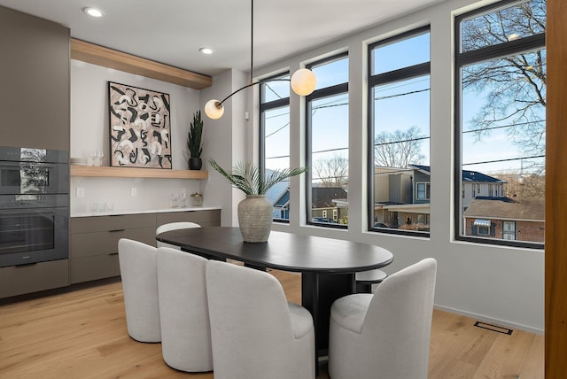 dining room featuring visible vents, recessed lighting, a bar, light wood finished floors, and baseboards