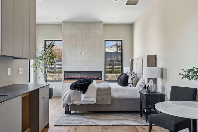 bedroom with visible vents and a glass covered fireplace