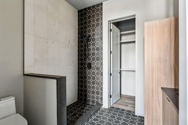 bathroom with a tile shower and toilet