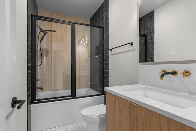 bathroom featuring tile patterned flooring, combined bath / shower with glass door, toilet, and vanity