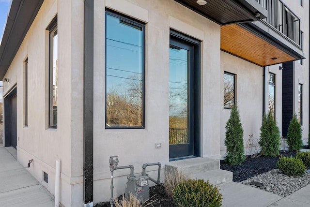 entrance to property with crawl space, a balcony, and stucco siding