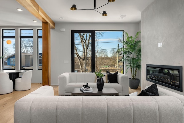 living room with a glass covered fireplace, recessed lighting, wood finished floors, and a wealth of natural light