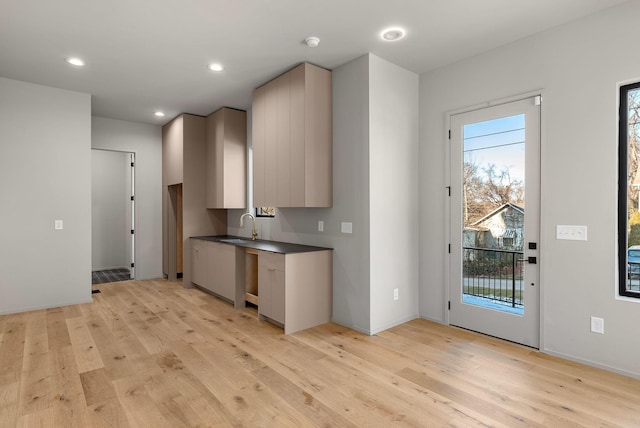 kitchen featuring light wood-style flooring, recessed lighting, gray cabinets, a sink, and dark countertops