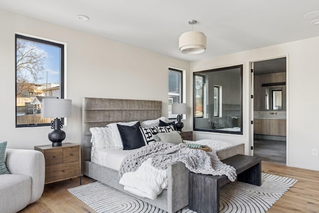 bedroom with a sink, ensuite bath, and wood finished floors