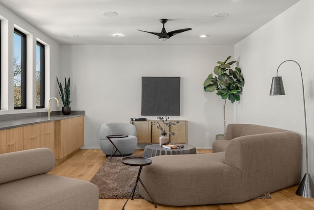 living room featuring light wood-type flooring, baseboards, and a ceiling fan