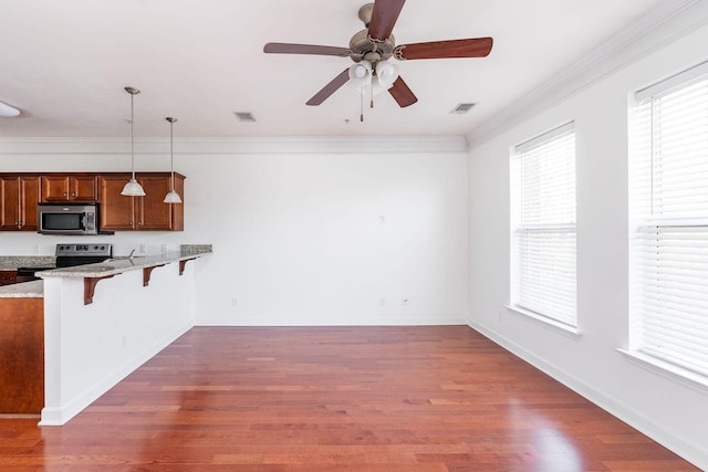 kitchen featuring stainless steel appliances, a kitchen bar, dark wood finished floors, and crown molding