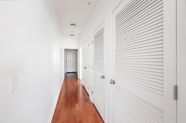 hallway featuring wood finished floors and baseboards