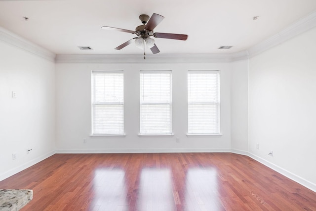 empty room featuring crown molding, wood finished floors, and visible vents