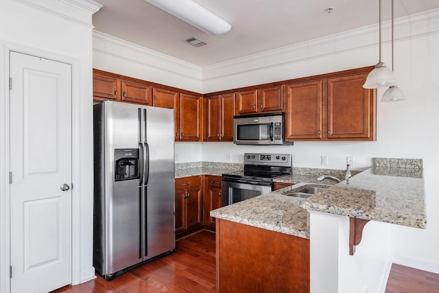 kitchen featuring dark wood finished floors, appliances with stainless steel finishes, a peninsula, and ornamental molding