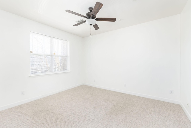 carpeted spare room with a ceiling fan and baseboards