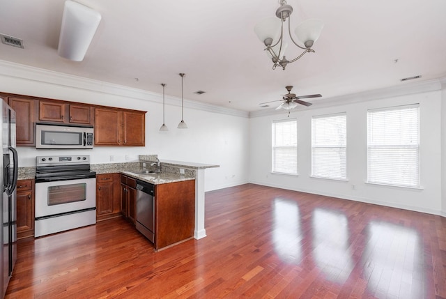 kitchen featuring a peninsula, ornamental molding, stainless steel appliances, a sink, and ceiling fan with notable chandelier