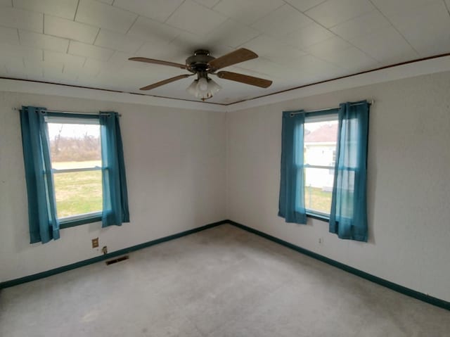 carpeted empty room featuring a ceiling fan, visible vents, and baseboards