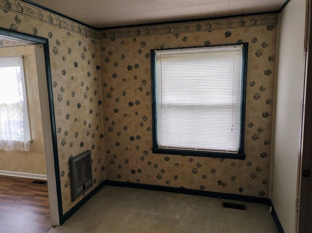 empty room with heating unit, visible vents, wallpapered walls, and baseboards