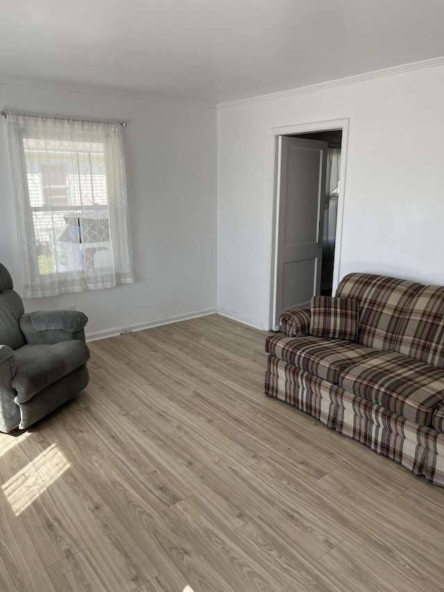 living room with light wood-style flooring, crown molding, and baseboards