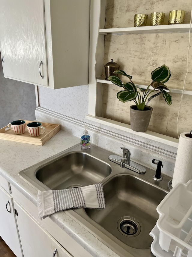 room details with white cabinetry, light countertops, and a sink