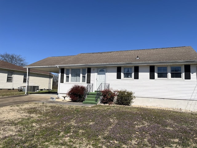 view of front of house with a carport, concrete driveway, and roof with shingles