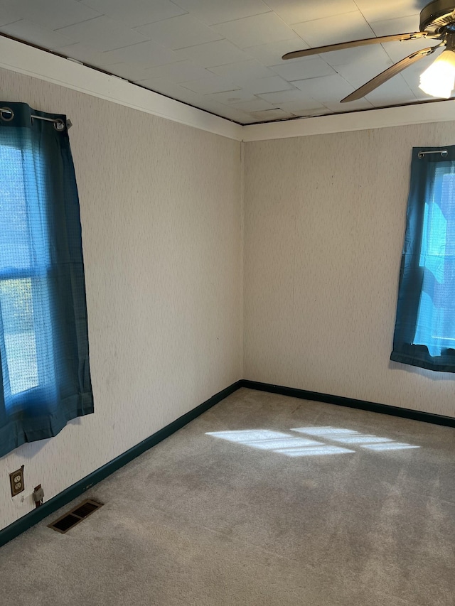 spare room with a wealth of natural light, visible vents, carpet floors, and ceiling fan