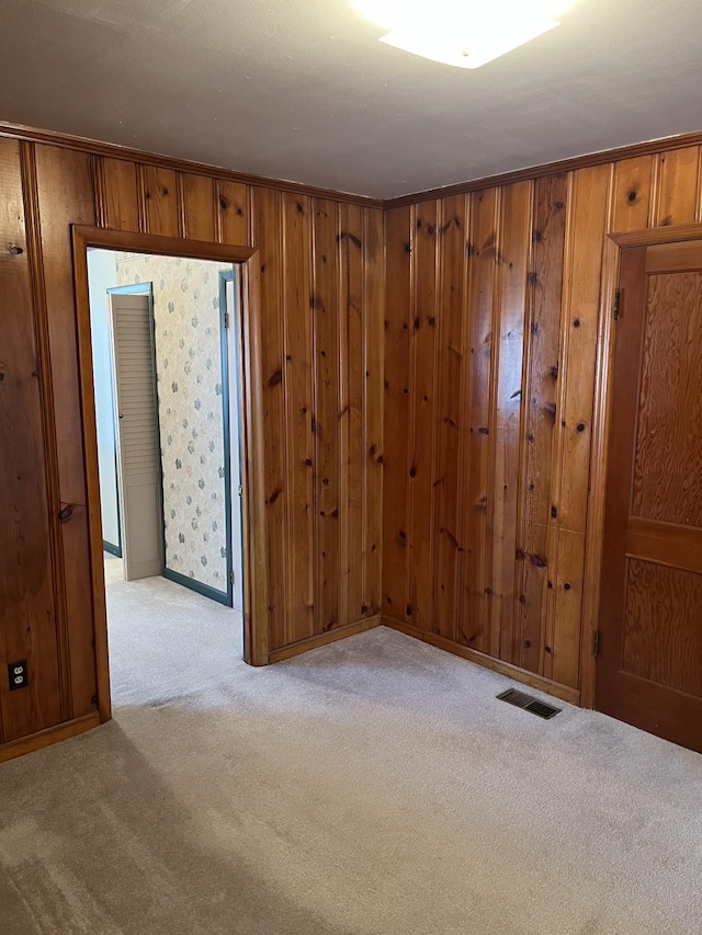 carpeted spare room with crown molding, baseboards, and visible vents