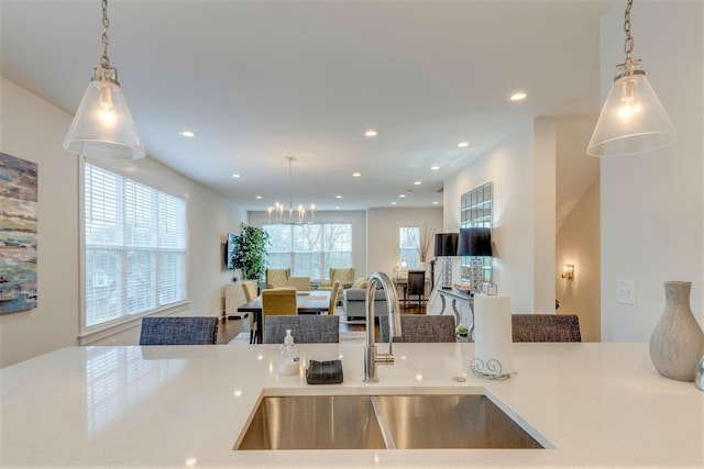 kitchen featuring open floor plan, recessed lighting, an inviting chandelier, hanging light fixtures, and a sink