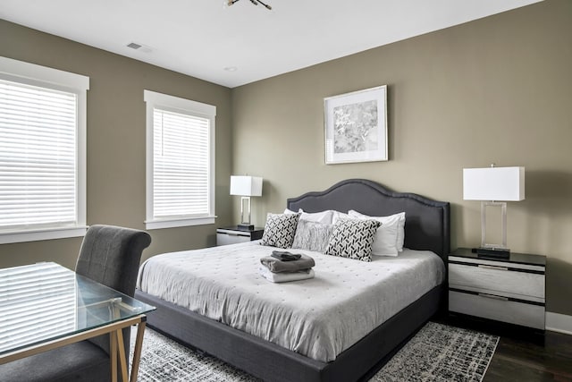 bedroom with visible vents, multiple windows, and wood finished floors