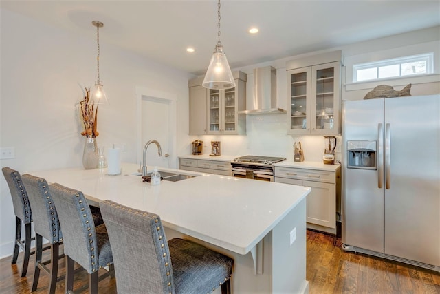 kitchen with a breakfast bar, a sink, appliances with stainless steel finishes, wall chimney range hood, and tasteful backsplash