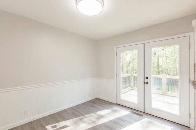 entryway with french doors, wood finished floors, visible vents, and a wainscoted wall