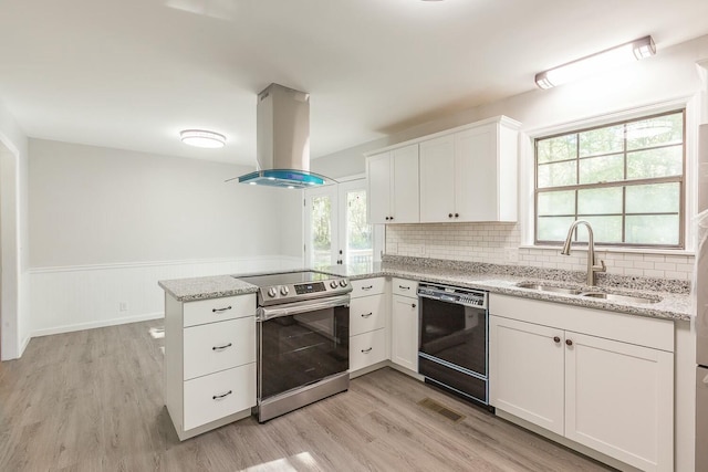 kitchen with dishwasher, a peninsula, island exhaust hood, stainless steel range with electric cooktop, and a sink