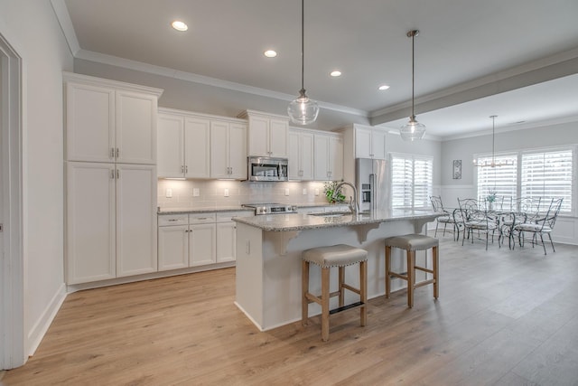 kitchen featuring a breakfast bar area, an island with sink, light wood-style flooring, stainless steel appliances, and white cabinetry