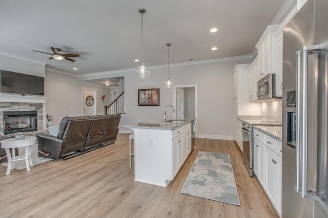 kitchen with a sink, a kitchen breakfast bar, open floor plan, stainless steel appliances, and white cabinets