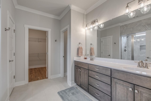 bathroom with double vanity, a stall shower, a sink, ornamental molding, and a walk in closet