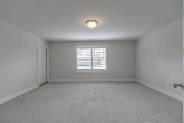 unfurnished room featuring visible vents, light colored carpet, and baseboards