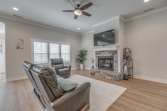 living area with visible vents, baseboards, ceiling fan, ornamental molding, and a fireplace