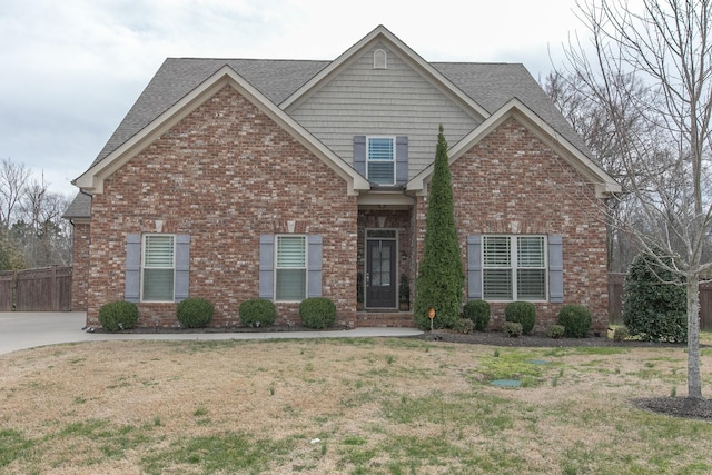 craftsman inspired home with brick siding, a front lawn, and roof with shingles