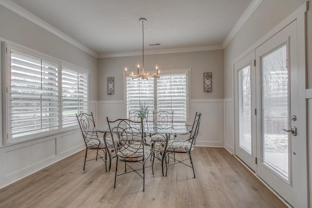 dining space featuring light wood-type flooring, plenty of natural light, and an inviting chandelier