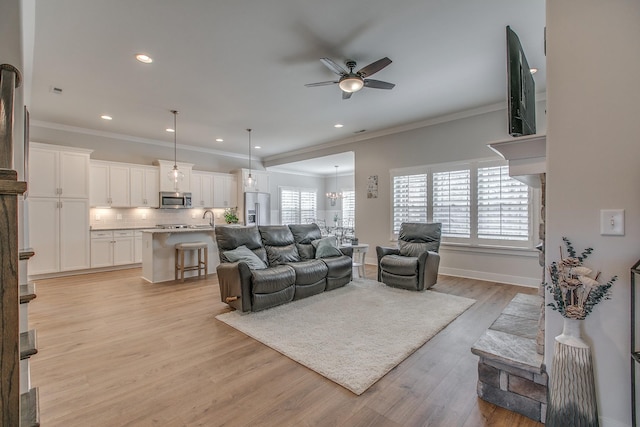 living room featuring plenty of natural light, ceiling fan with notable chandelier, and light wood-style floors