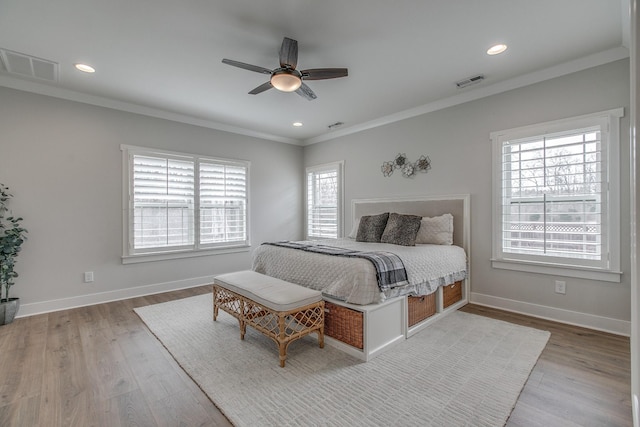 bedroom with wood finished floors, visible vents, and ornamental molding