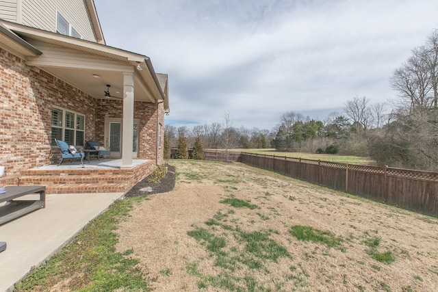 view of yard with a fenced backyard, ceiling fan, and a patio