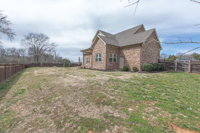 view of property exterior with brick siding, a lawn, and a fenced backyard