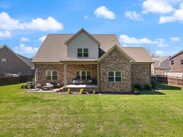 rear view of property with a lawn, a patio area, a fenced backyard, and brick siding