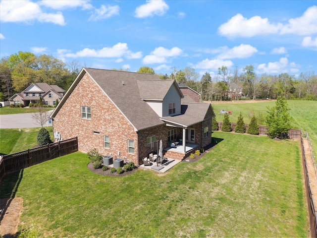 exterior space with a fenced backyard, cooling unit, a patio area, a lawn, and brick siding