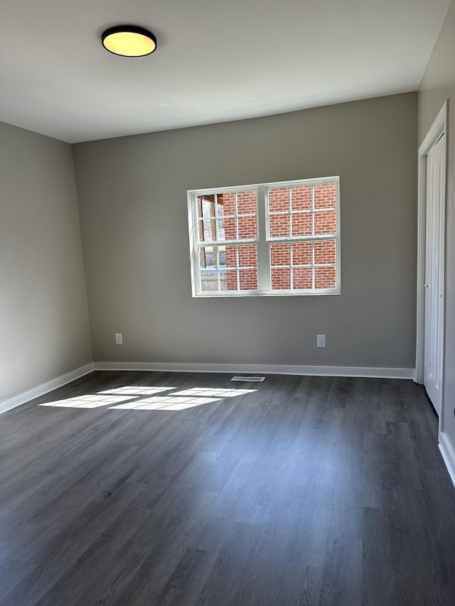 empty room with visible vents, baseboards, and dark wood-style flooring