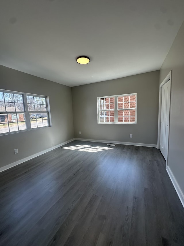 unfurnished room featuring baseboards and dark wood-style flooring