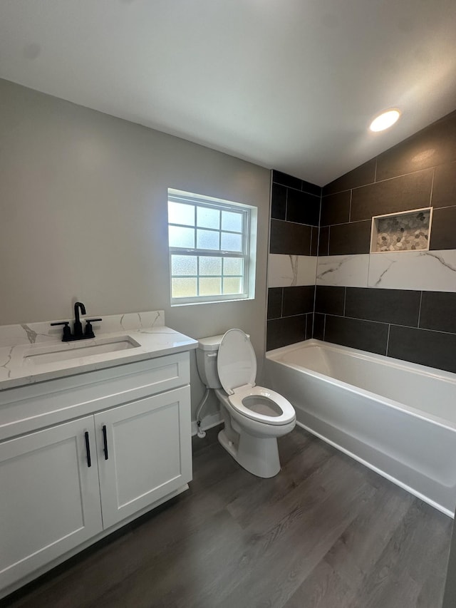 bathroom with vanity, wood finished floors, lofted ceiling,  shower combination, and toilet