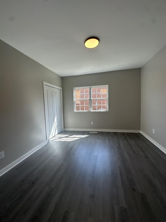 spare room with dark wood finished floors and baseboards