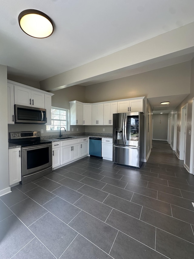 kitchen with a sink, white cabinets, baseboards, and stainless steel appliances