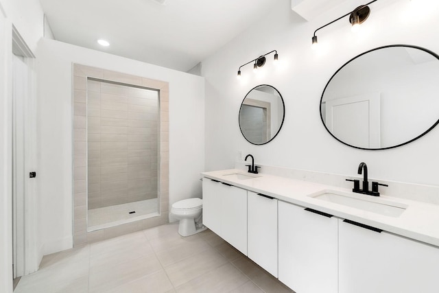 bathroom featuring a tile shower, tile patterned flooring, toilet, and a sink