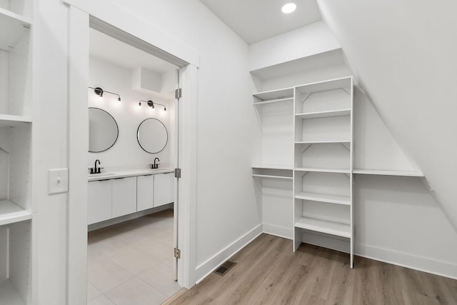 walk in closet featuring a sink, visible vents, and light wood-type flooring