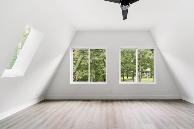 additional living space featuring a ceiling fan, wood finished floors, baseboards, visible vents, and vaulted ceiling