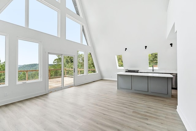 unfurnished living room with a sink, baseboards, and light wood-style floors